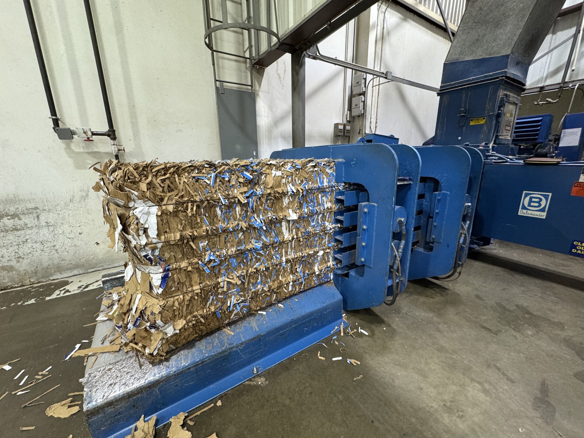 Horizontal auto-tie baler producing dense OCC cardboard bales at recycling facility