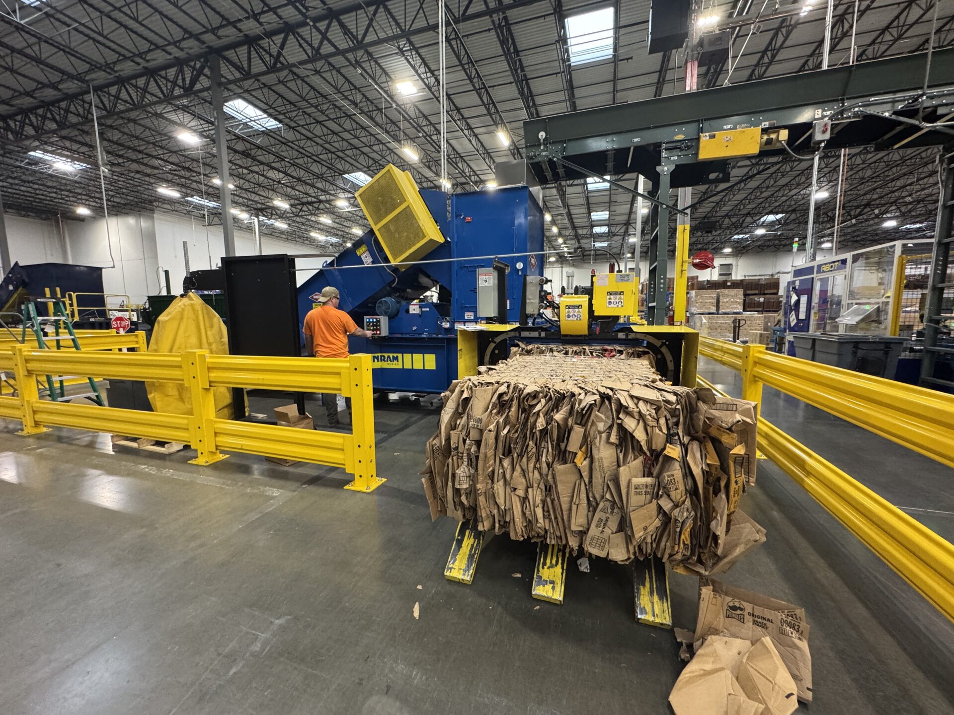 Baler infeed conveyor system in distribution center moving OCC cardboard from receiving dock to baler hopper