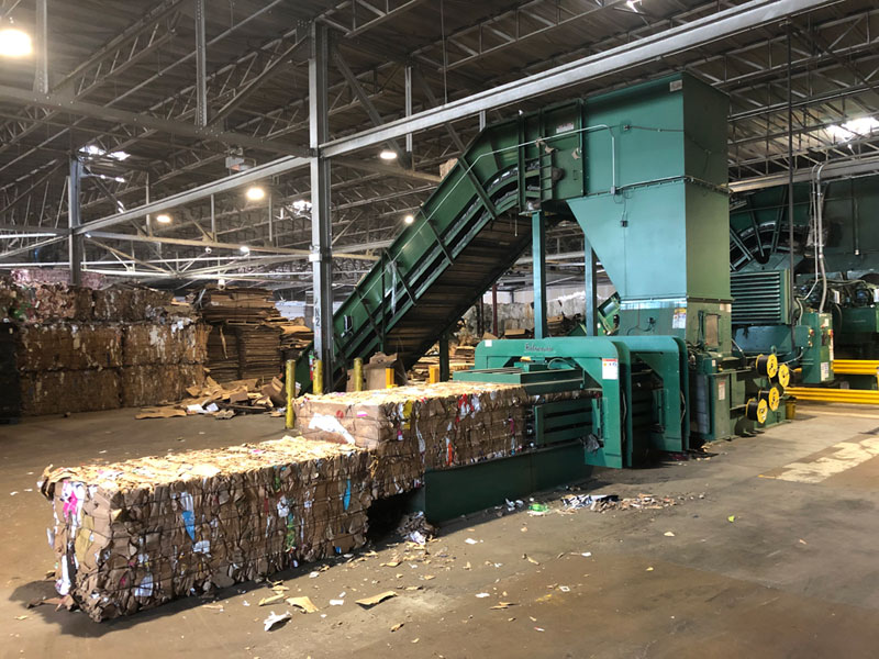 Corrugated OCC baler producing dense mill-ready cardboard bales at recycling facility installed by HMS